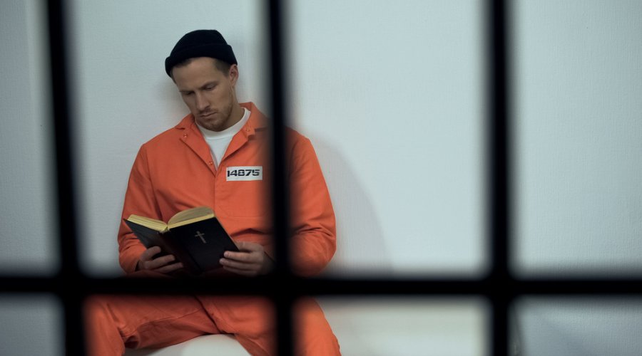 man reading Bible in jail